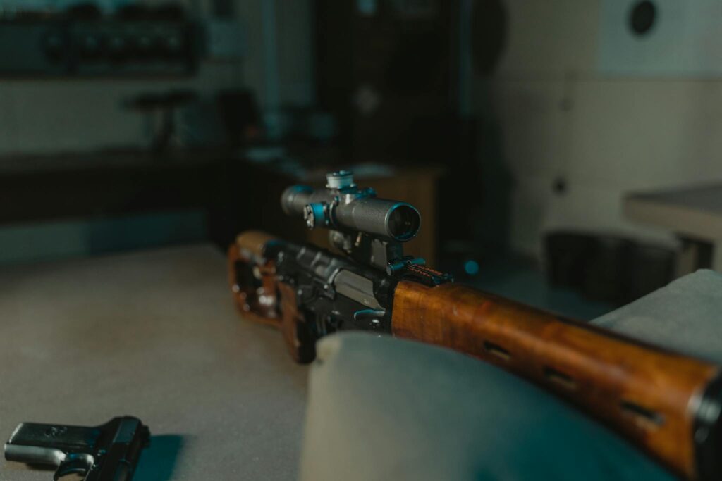 Close-up view of a sniper rifle with a scope on display indoors, suitable for military or hunting themes.